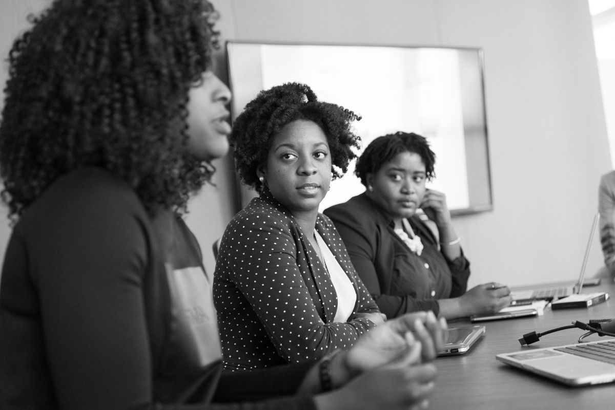 Three Black women sharing ideas in a professional meeting