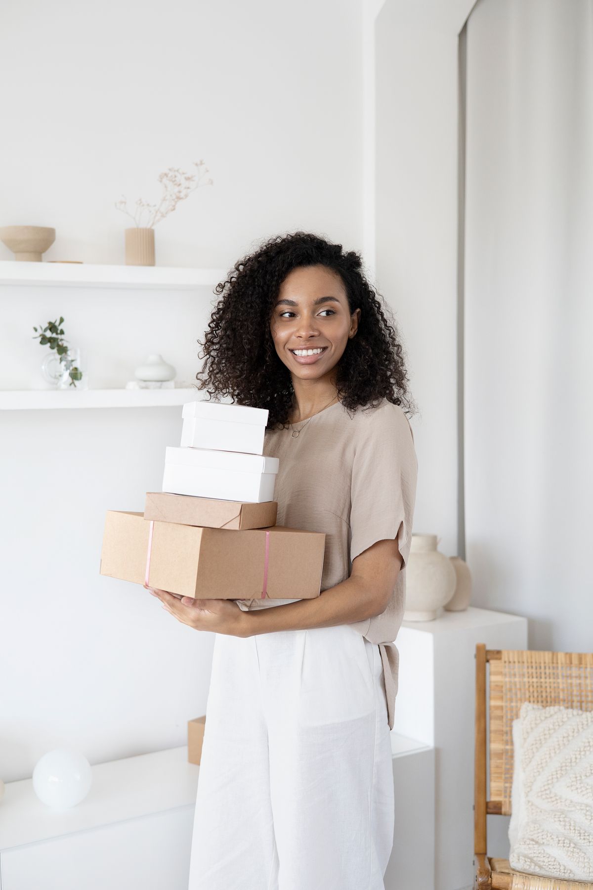 Black woman carrying boxes into a bright home